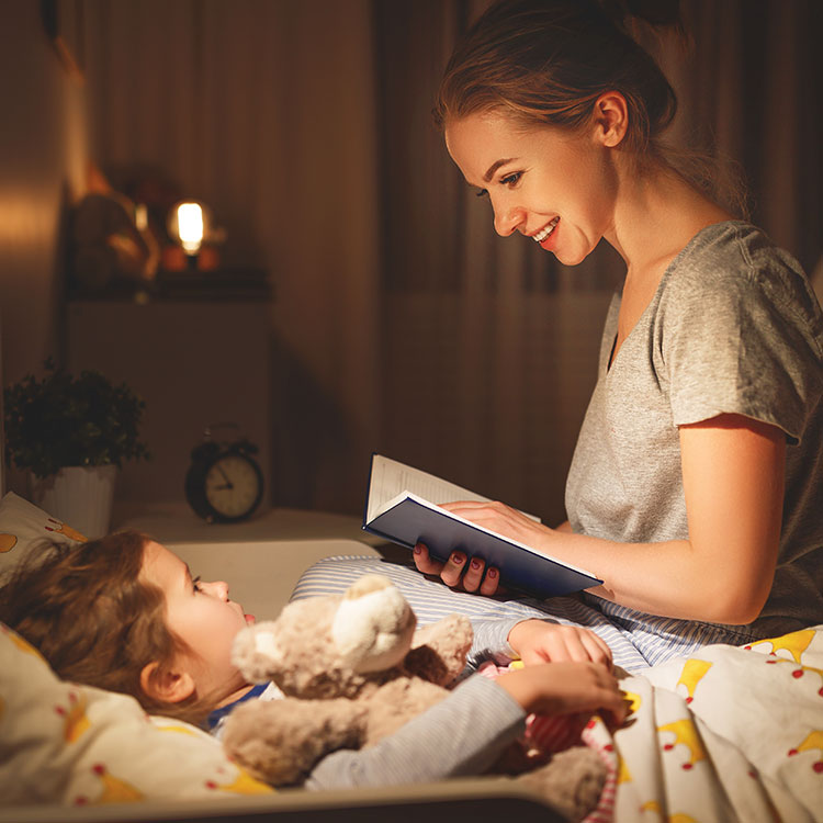 Mutter liest Kind eine Gute-Nacht-Geschichte vor.