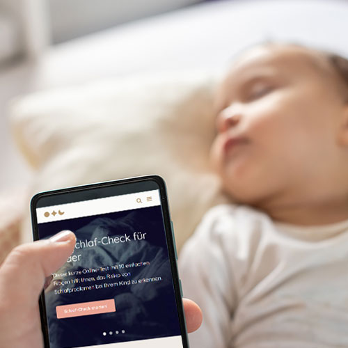 Mutter besucht Webseite schlafprobleme-bei-autismus.de. Im Hintergrund ein schlafendens Kind.